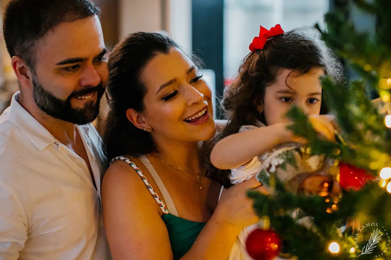 Família decorando a árvore de Natal durante ensaio fotográfico em casa