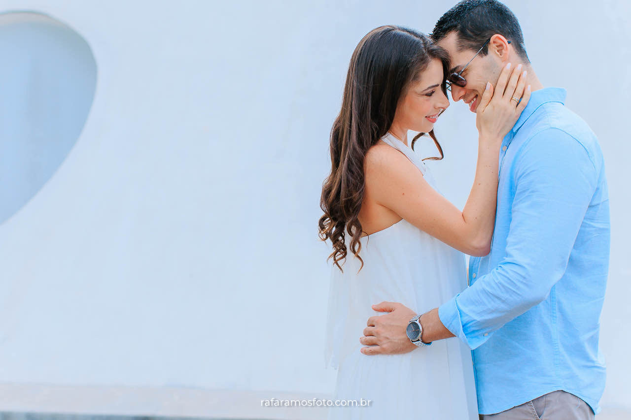 Casal abraçado durante ensaio pré-casamento em São Paulo com cenário arquitetônico da Oca