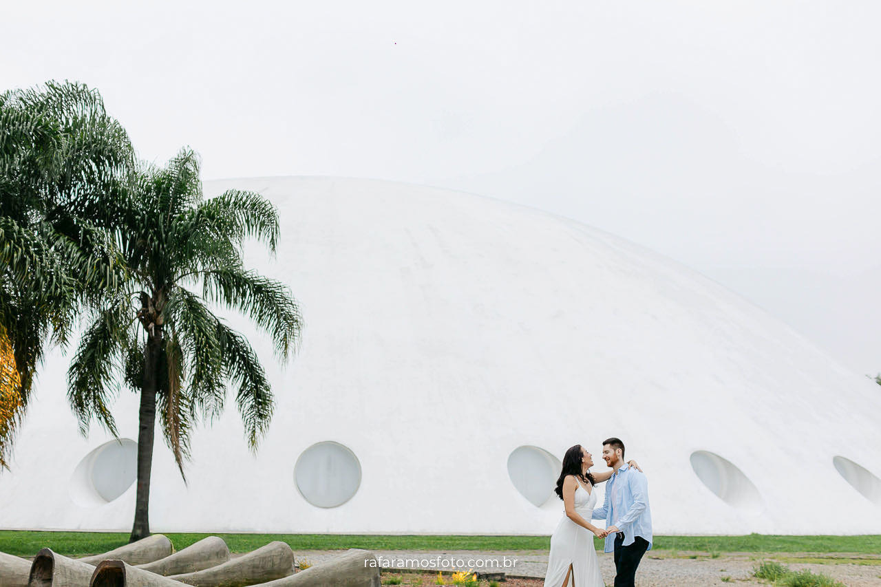 Ensaio de casal no Parque Ibirapuera em São Paulo com os noivos caminhando diante de uma arquitetura branca